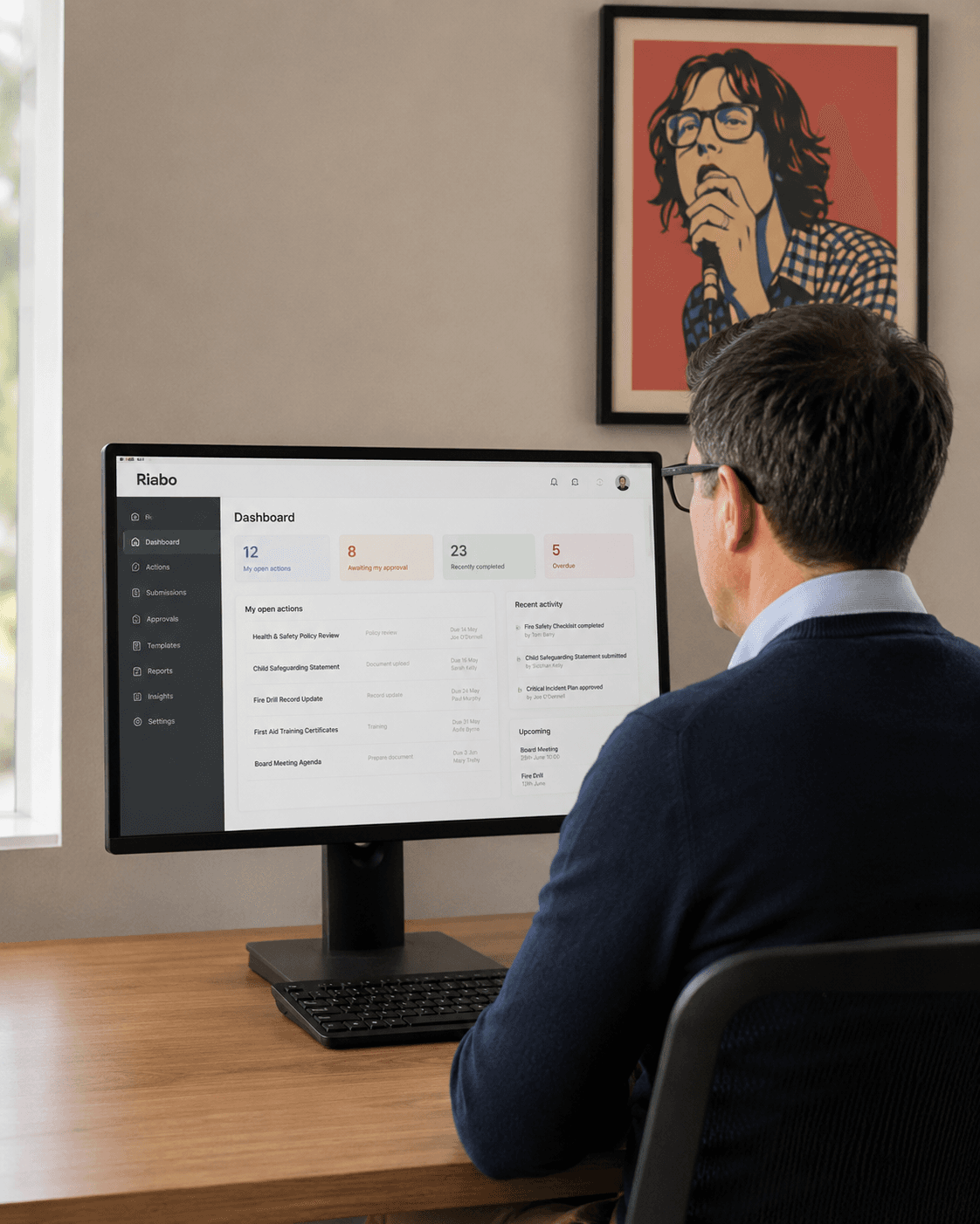 A school principal reviewing the Riabo dashboard on a desktop monitor in his office.